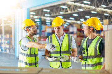 Three warehouse workers using a digital tablet while recording inventory. Logistics employees...