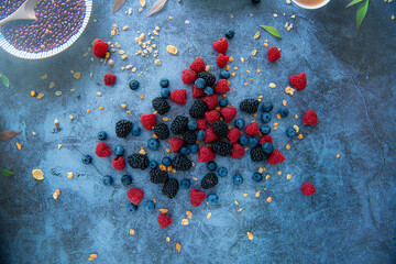 Blueberries, raspberries and blackberries shot top down on a blue stone table
