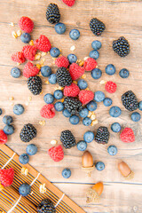 Blueberries and raspberries, blackberry in a wooden carpet on old wood background