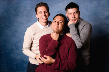 Group of 3 men in jersey on blue background in 90's yearbook style. Posing as funny family
