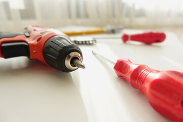 DIY tools and materials are arranged on a wooden floor, illuminated by natural light