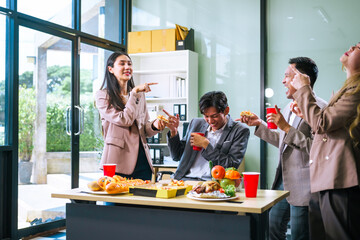 Four Asian friends, two men and two women, celebrate in an office party. They enjoy a fun-filled with food, drinks, and laughter, bonding over teamwork and friendship.