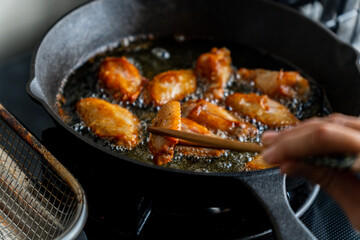 chicken wing fried until golden brown in bubbling hot vegetable oil, home cooking concept
