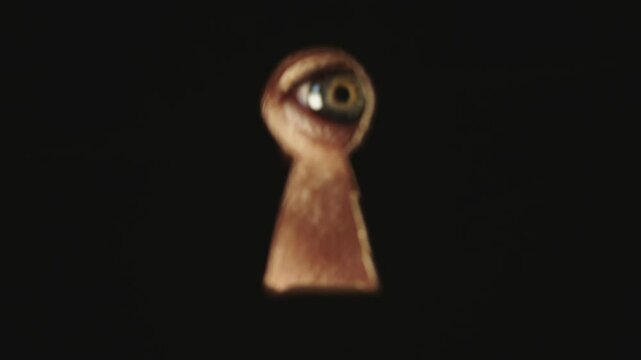 Male blue eye looking through the keyhole. The concept of voyeurism, curiosity, Stalker, surveillance and security