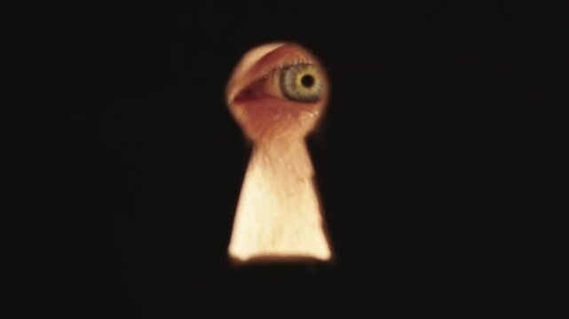 Male blue eye looking through the keyhole. The concept of voyeurism, curiosity, Stalker, surveillance and security