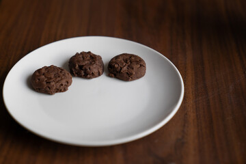 tres galletas de chocolate en plato blanco con espacio para texto