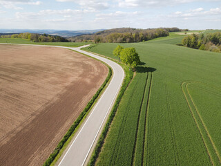 Aerial view of a paved road between farm fields in the landscape 