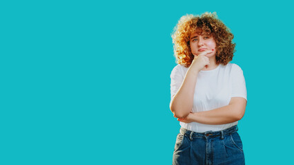 Confused woman deep in thought clueless puzzled hand on chin isolated on blue empty space...