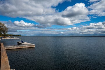 Obraz premium Panoramic aerial view of the Thousand Islands along the U.S.-Canada border, showcasing countless green islands with boat docks nestled along shimmering waters under a clear blue sky.