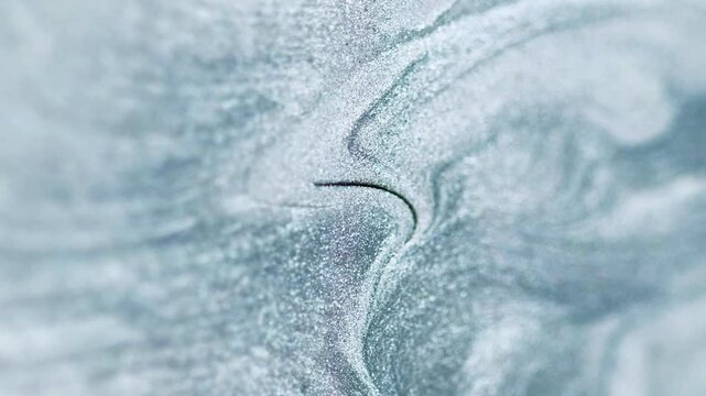 Liquid silver texture. Shimmer ink flow. Defocused gray color metallic glitter sand particles sparkling paint fluid spill motion abstract art background.