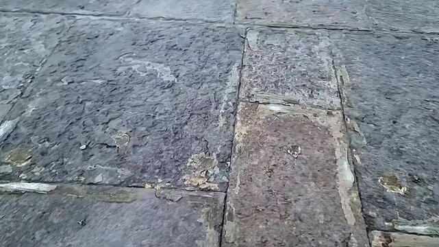 Looking down at weathered rustic old stone pavement slabs vintage street pattern