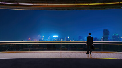 Businessman looking at city skyline at night from balcony 3d rendering