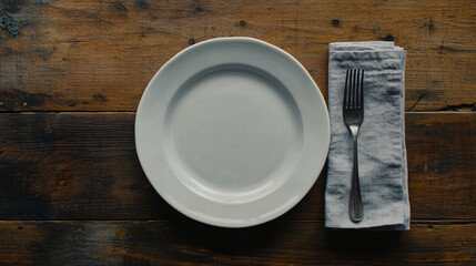 empty white plate with fork and napkin on wooden tabletop
