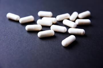 Creatine capsules on dark paper background. Soft focus. Copy space.	