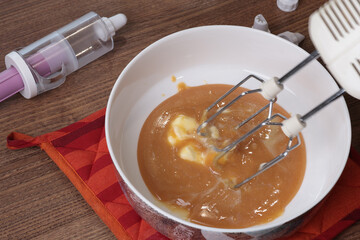 Process of preparation of caramel cream. Beating caramel, egg white and butter with mixer. Baking at home. Close-up. 