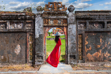 Asian woman in ao dai dress visits the Royal Palace of the Nguyen Dynasty in Hue, Vietnam.