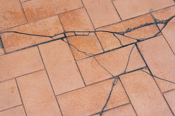 Broken floor. Tile with large diagonal cracks and chips. Problems of the construction of houses,...