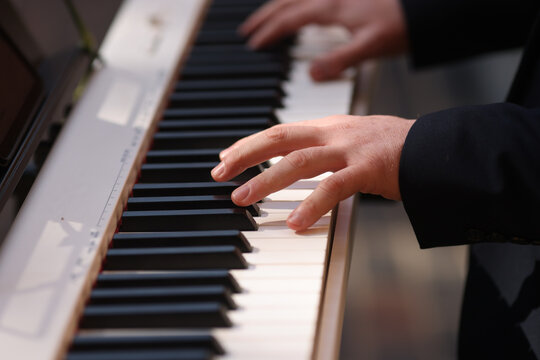 Details with the hands of a man playing an electric piano