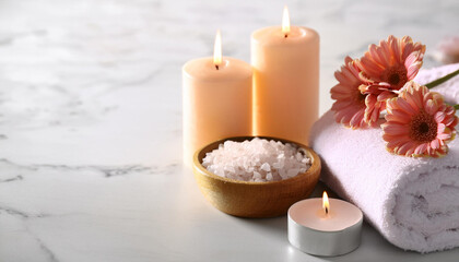 Spa composition with burning candles, flowers and sea salt on white marble table