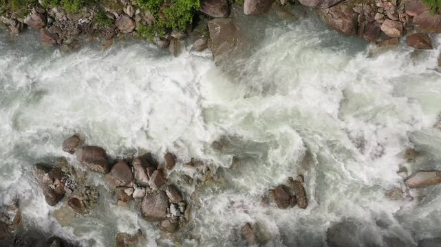 Clear stream running through stone boulders Abundant river flowing on stone bottom in slow motion. Aerial view of a pristine mountain river in Italy's Alps.