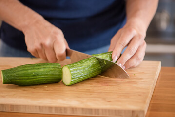 Close up of a womans hands chopping a cucumber