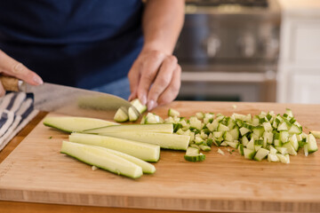 Womans hands chopping a cucumber
