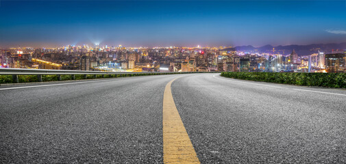 Serene Night Road Leading to a Vibrant City Skyline