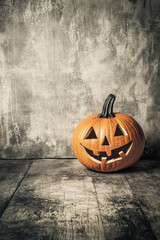 A pumpkin with a scary face is sitting on a wooden floor. The pumpkin is orange and has a smile on its face