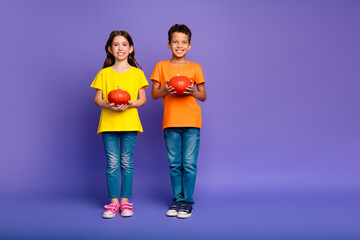 Full size photo of charming two little children hold halloween pumpkins wear trendy orange yellow outfit isolated on violet background