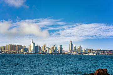 Obraz premium Vibrant City Skyline Against a Clear Blue Sky Over Calm Waters
