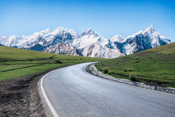 Naklejka premium Asphalt highway road and green grassland with snow mountain natural landscape. Car background.