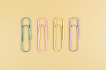 Top view of colorful paperclips on yellow background. School, office wallpaper. Flat lay, copy space.