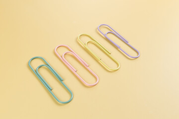 Top view of colorful paperclips on yellow background. School, office wallpaper. Flat lay, copy space.