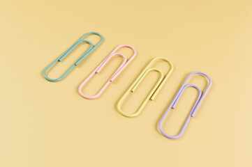 Top view of colorful paperclips on yellow background. School, office wallpaper. Flat lay, copy space.
