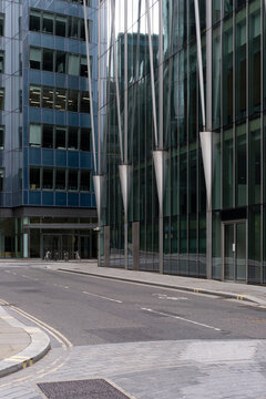 This image showcases an empty urban street flanked by modern glass skyscrapers, highlighting the calm and orderly side of urban life with sleek architectural lines.