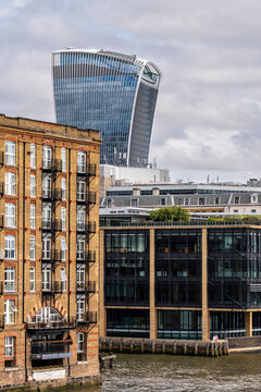 A view of an iconic riverfront building beside a modern skyline, capturing the blend of historical architecture and sleek contemporary structures along the riverbank in London
