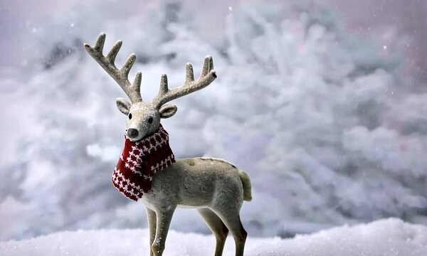 Neige tombant sur un renne blanc portant une &eacute;charpe rouge et blanche, ambiance de No&euml;l et magie des f&ecirc;tes de fin d'ann&eacute;e