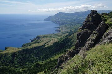 Stunning coastal view from rocky cliffs overlooking a serene blue ocean and lush landscapes