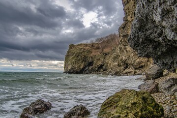Waves crashing against rocky shores beneath dramatic clouds on a stormy day by the coast