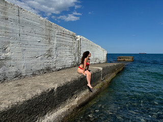 The breakwater of the sea is a lonely bather. The girl in the red bikini	