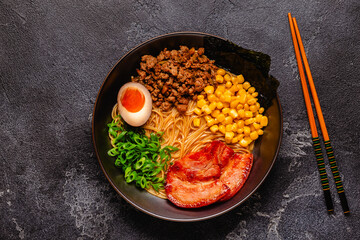 A bowl of ramen with noodles, meat and green onions.