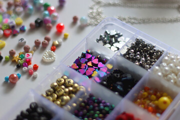 Colorful beads, letter beads, threads and other jewelry making supplies on white background. Making friendship bracelets concept. Selective focus.