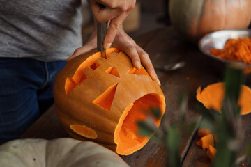 Close-up of hands skillfully carving a pumpkin into a jack-o'-lantern. Perfect for Halloween themes...