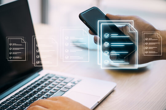 Close up of businessman hand using cellphone and laptop at desk with creative digital document on blurry office background. Online survey and digital form checklist. Vote concept. Double exposure.