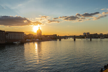 Naklejka premium Golden sunset over Garonne river with views on the the pedestrian Saint-Pierre bridge, Place Saint-Pierre and the Grave hospital seen from the riverside 