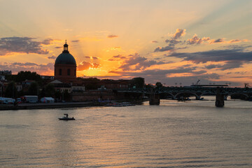 Obraz premium Golden sunset over Garonne river with views on the the pedestrian Saint-Pierre bridge, Place Saint-Pierre and the Grave hospital seen from the riverside 