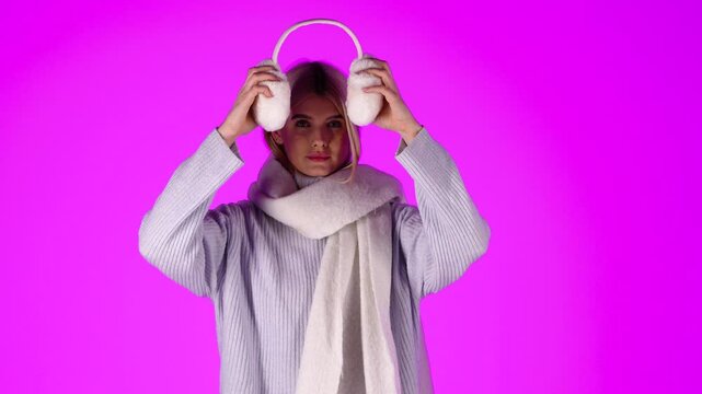 Pretty Blonde Woman Taking Off Her Winter Earmuffs, Stylish Grey Winter Clothing, Studio Portrait