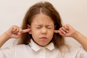 Portrait of caucasian child close ears by fingers on white background