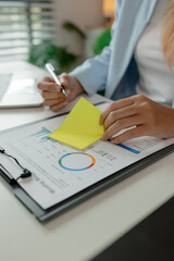 a businesswoman is working in her office and writing a note, a female employee is writing a brief...