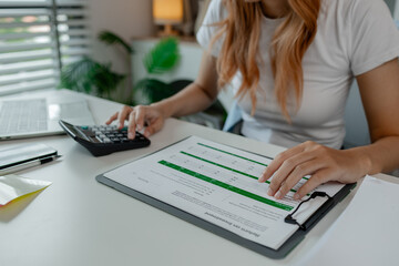 a businesswoman is using calculator in the office, checking company balance from paperwork, calculate finance information, calculating statistic marketing report